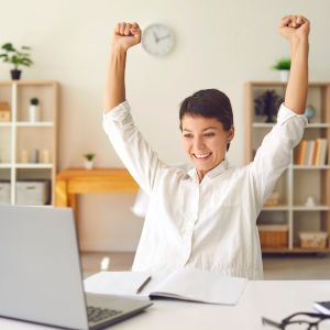 Mulher no computador comemorando o sucesso da sua campanha de financiamento coletivo