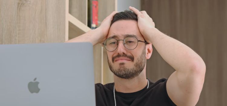 Homem com a mão na cabeça triste em frente ao computador