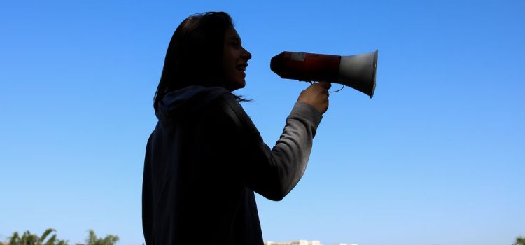 Pessoa com megafone na mão divulgando vaquinha online na rua