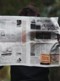 Pessoa segurando um jornal na mão e lendo notícias sobre vakinha online.