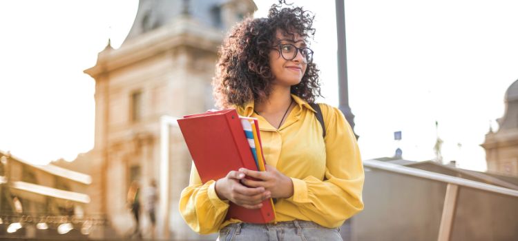 Estudante com livros na mão na rua