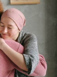 Pessoa com câncer sendo abraçada pela amiga
