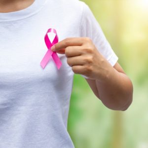 Mulher segurando o símbolo do câncer de mama na mão
