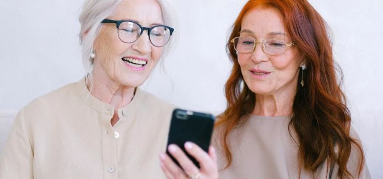 Duas senhoras olhando para o telefone celular na mão