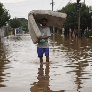 Homem carregando colchão durante enchente no Rio Grande do Sul